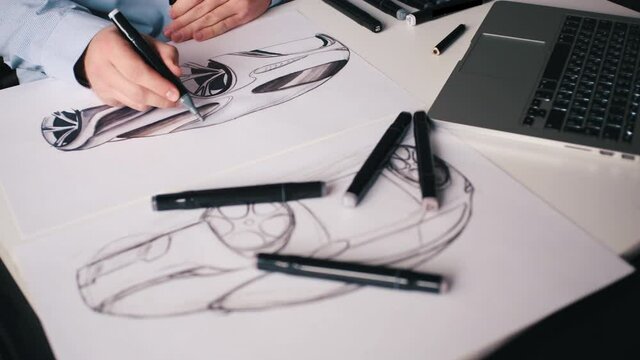 A man draws a new design project for a future car at home