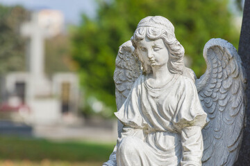 Sculpture of a little angel on a tomb in cemetery. Selective focus