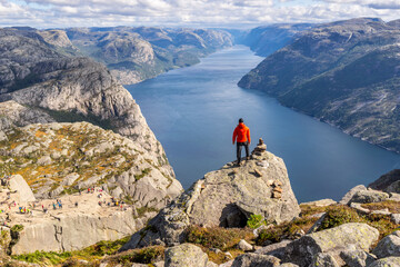 Fototapeta premium Hiker looking over Preikestolen (Pulpit Rock) above Lysefjord near Stavanger, Norway