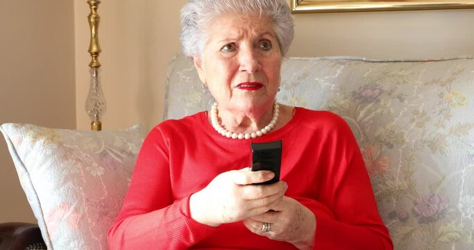 Portrait of a eldery lady watching television and looking shocked at home