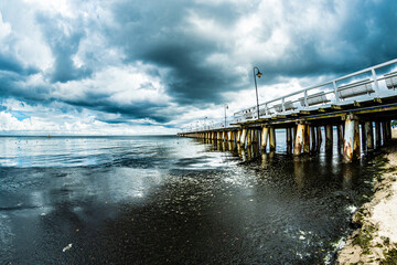 Obraz premium Gulf and pier under cloudy sky