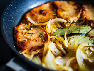 Pork steaks in frying pan with onion

