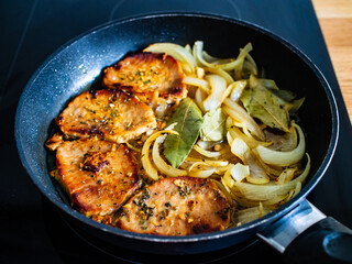 Pork steaks in frying pan with onion
