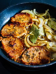 Pork steaks in frying pan with onion
