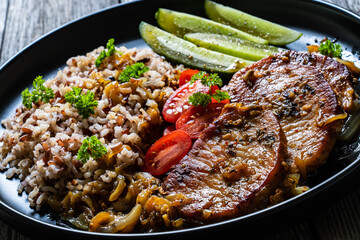 Roasted meat, buckwheat and pickled cucumbers on wooden table
