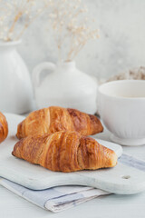Delicious breakfast with fresh croissants and cup of coffee on a white wooden background. Delicious Baking