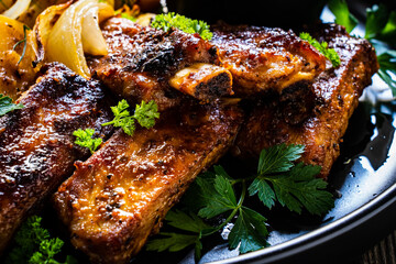 Tasty roasted ribs with baked potatoes vegetables on wooden table
