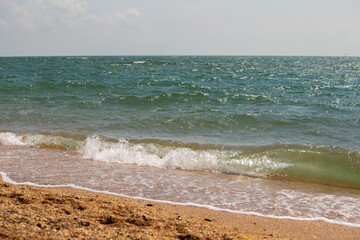 Waves roll over the sandy shore. The white lambs of the waves disappear into the sand.