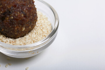 Dried fruit and nuts candy. Made at home in isolation during the epidemic. Lies on white sesame seeds.