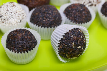 Dried fruit and nut sweets. Some are sprinkled with sesame seeds. Made at home in self-isolation during the epidemic. They lie in paper capsules.