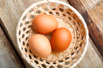 cracked eggs in a wicker plate on a wooden table.