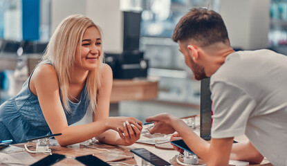 Close up side view of pretty happy excited hipster young love couple testing new smart gadgets in a tech store.