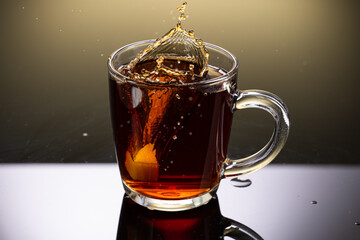 Brew black tea from a sausage bag in a transparent mug with reflection on a gradient background