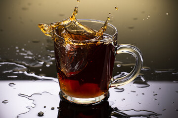 Brew black tea from a sausage bag in a transparent mug with reflection on a gradient background