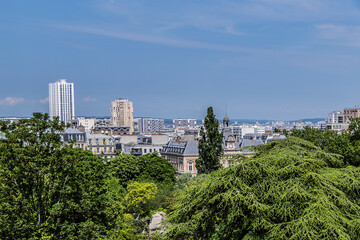 Buttes-Chaumont Park (Parc des Buttes-Chaumont, 1867) with Paris skyline in the background. Parc des Buttes-Chaumont - Public Park situated in northeastern Paris, fifth-largest park in Paris. France.