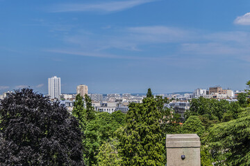 Fototapeta na wymiar Buttes-Chaumont Park (Parc des Buttes-Chaumont, 1867) with Paris skyline in the background. Parc des Buttes-Chaumont - Public Park situated in northeastern Paris, fifth-largest park in Paris. France.
