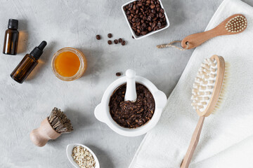 Homemade body scrub made with ground coffee, honey and oatmeal in a jar on gray concrete table.