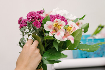 Florist at work: pretty young woman making fashion modern bouquet of different flowers.
