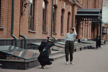 Young female photographer strolling along alley with girlfriend. Travelers walk in the city. Look attractions city.