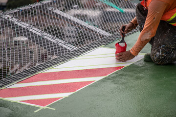 worker painting details on helipad with safety equipment