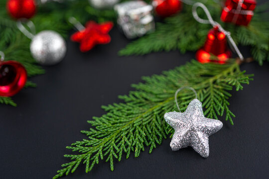 Christmas composition with silver star on the fir tree. Black Blurred focus background with gift and red toys. Winter holiday theme. Space for text.