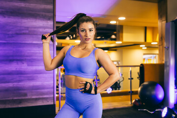  Sexy girl doing stretch marks sitting on a mat in the gym, in a blue tracksuit