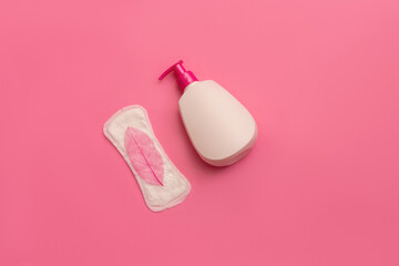 Sanitary napkin and plastic bottle on pink background. Female health concept
