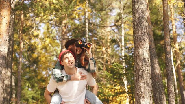 Carefree travellers enjoy the nature, use binoculars, smile. Happy caucasian couple having fun during hike, travel in the forest, on mountains.