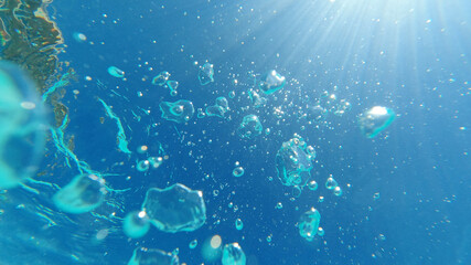 Underwater bubbles emerging to turquoise sea surface