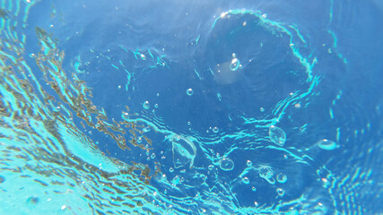 Underwater bubbles emerging to turquoise sea surface
