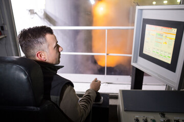 operative watching computer monitor on industrial site