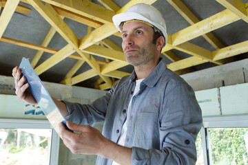 man builder stands with clipboard indoors
