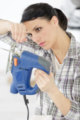 woman fixes a bar on a miter saw in workshop