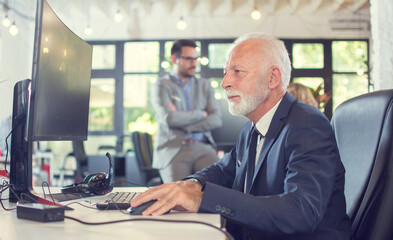 Senior businessman in formalwear using computer in office.