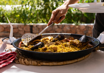 hands serving a spanish paella