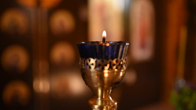 A small candle in a gold stand in the church burns out.