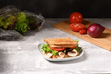 Sandwich with ham and fresh salad on the plate.