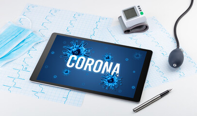 Tablet pc and doctor tools on white surface with CORONA inscription, pandemic concept