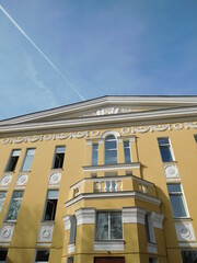 beautiful old yellow building with white balconies and white fretwork on the sky background