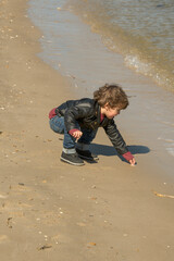 Young Boy Picking Something Up on Beach