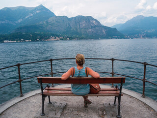 Fototapeta na wymiar Woman sitting on a bench in front Como Lake