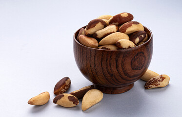 Brazil nuts in wooden bowl on white background