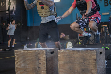 Chicos con mascarilla en un gimnasio realizando Cross training, box jumps