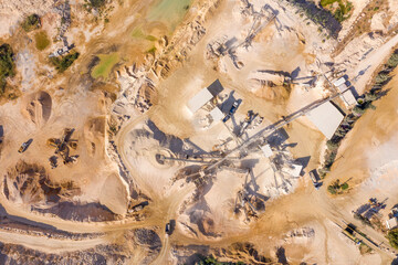 Aerial view of a large Quarry during work hours with Stone sorting conveyor belts and a truck passing.
