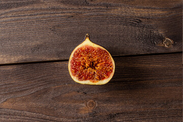 Half a fresh fig on an old dark dark wood table. Copy space flatlay on dark background.