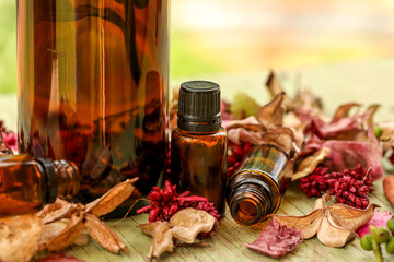 Selection of various sized amber bottles on wooden surface with dried flowers and leaves. Rustic wellness image.