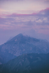A moutain top with cloudy, pink and purple sunrise in Slovenian Triglav national park.