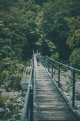 Fototapeta na wymiar Young female backpacker trekking over a suspension bridge over the river Soča in Slovenia