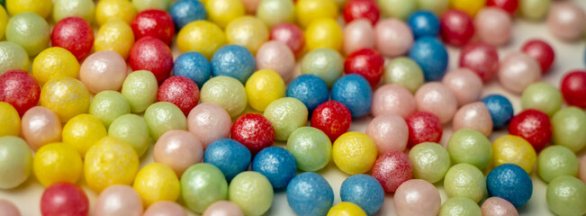 Fototapeta na wymiar Bright holiday banner. Sugar colored balls, pastry sprinkles as a background. Decoration for the cake. Macro