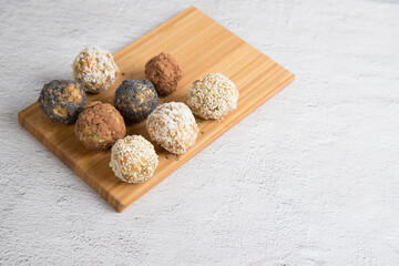 Homemade energy balls with dried fruits , nuts, sesame seeds, cocoa, almonds and poppy seeds on a cutting Board, light background. Vegan and vegetarian raw appetizer or food. Close-up